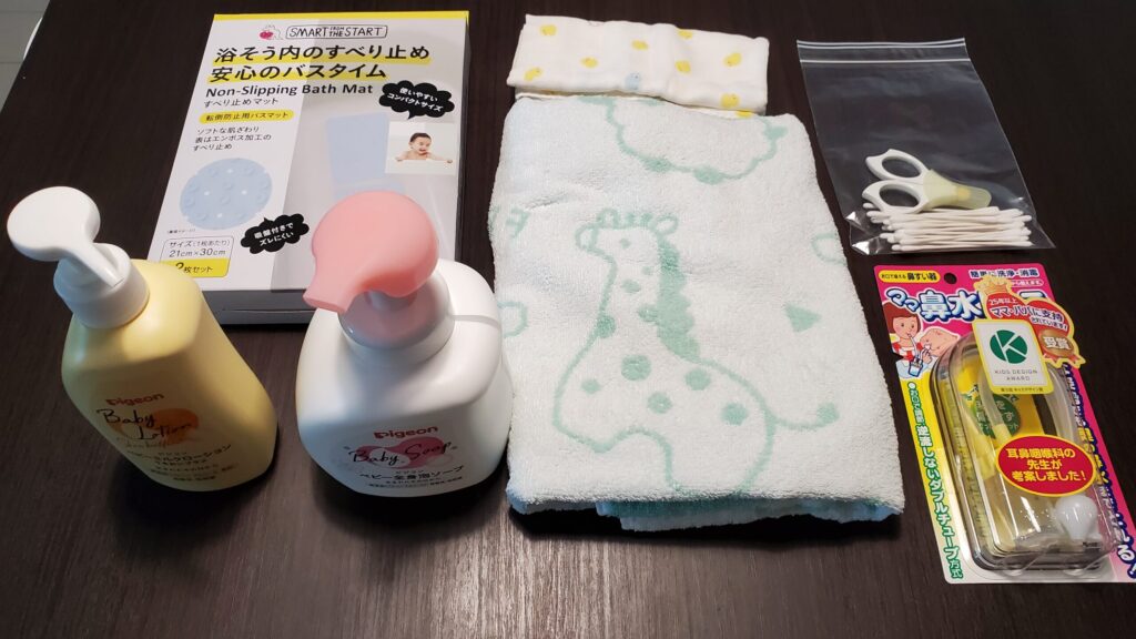 左上から順に洗面台沐浴用マット、ベビーローション、ベビーソープ、ガーゼ、バスタオル、爪切り、綿棒、鼻水吸引機